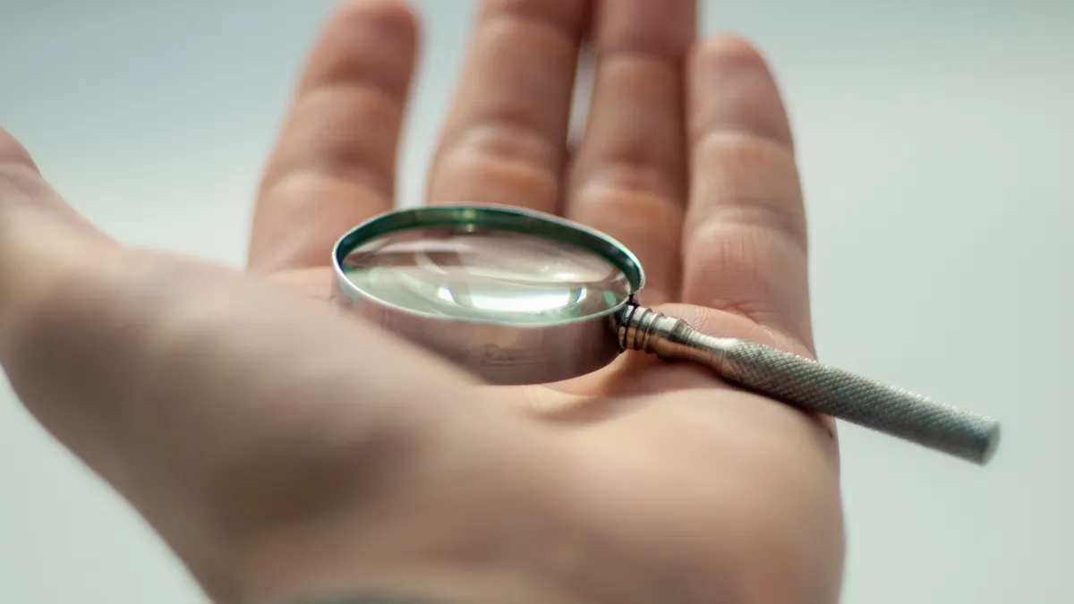 Hand holding a magnifying glass