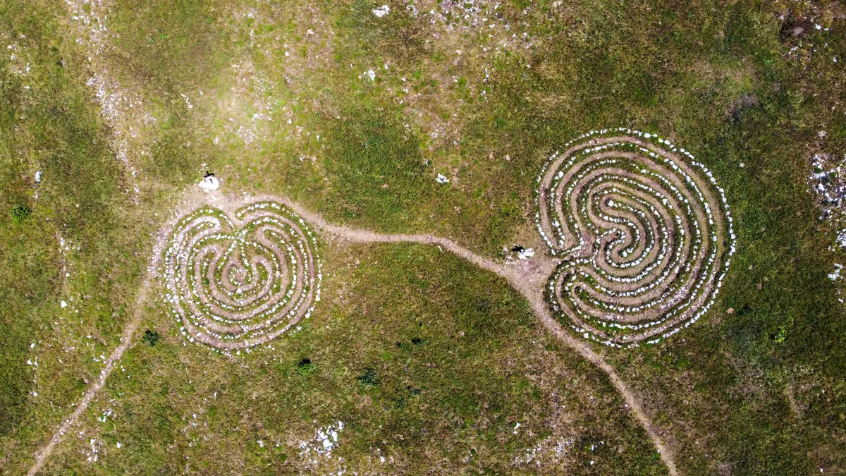 Two spiral hedge mazes connected by a path